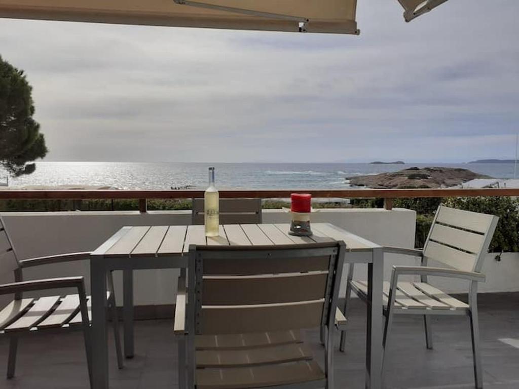 Aghia Marina的住宿－Breezy summer maisonette with exciting view!，阳台上配有桌椅和一瓶葡萄酒