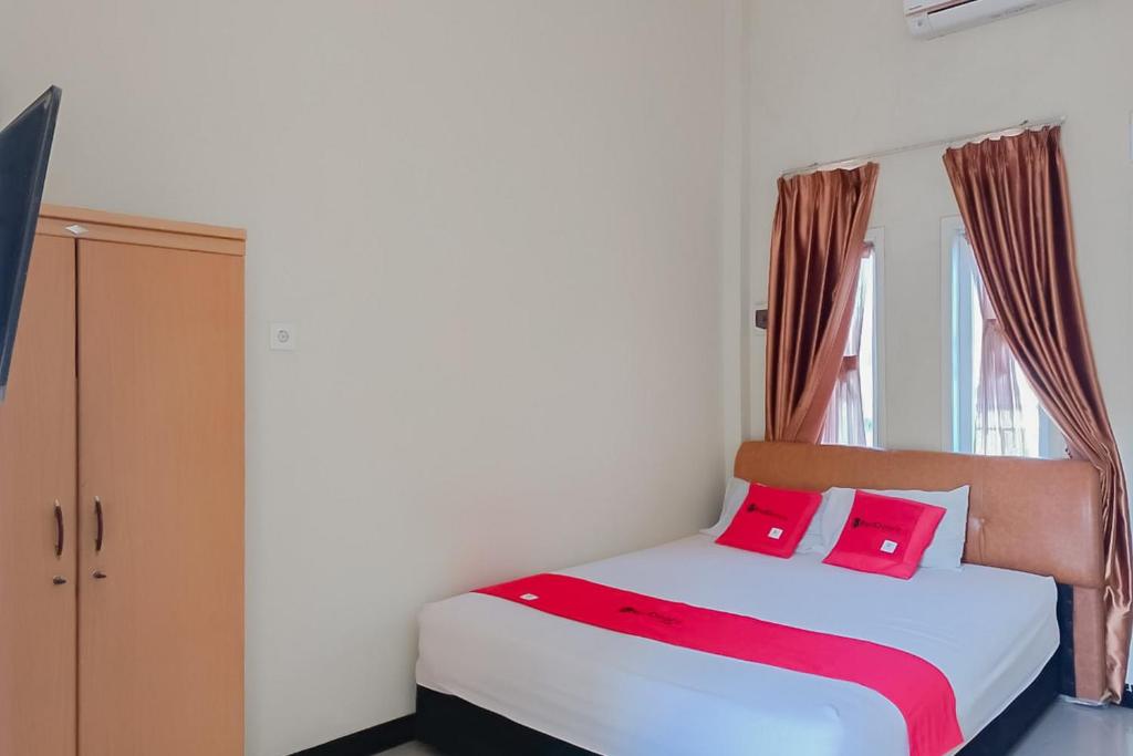 - une chambre avec un lit doté d'oreillers roses et d'une fenêtre dans l'établissement RedDoorz At Pelangi Guest House, à Balikpapan