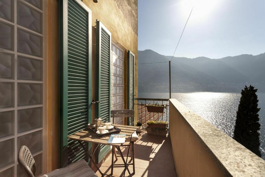 a balcony with a table and a view of the water at Ca Sbrisiga in Moltrasio in Moltrasio