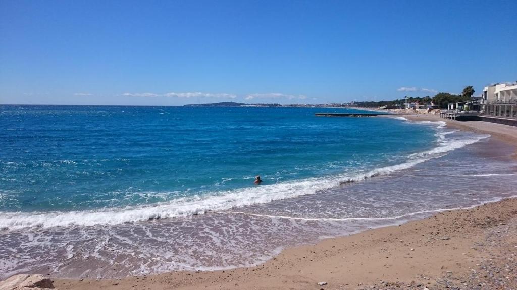 - une plage avec une personne nageant dans l'océan dans l'établissement Appartement bord de mer Marina Baie des Anges, à Villeneuve-Loubet