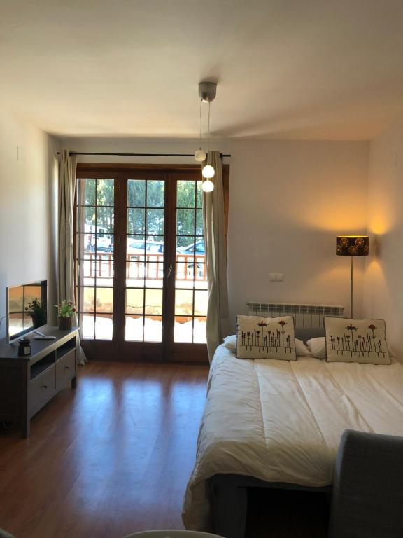 - une chambre avec un lit et une grande porte coulissante en verre dans l'établissement Apartamento frente Pistas de Esquí La Molina, à La Molina