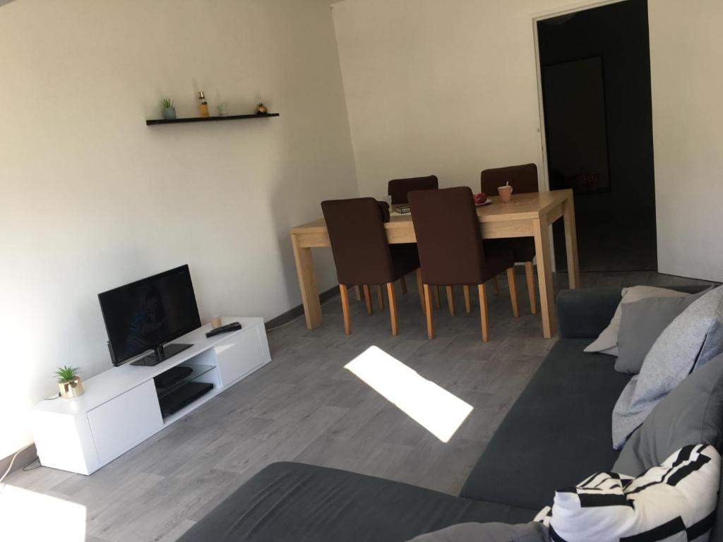 un salon avec une table, des chaises et une télévision dans l'établissement Poitiers appartement T2 à 15 mn du Futuroscope, à Poitiers
