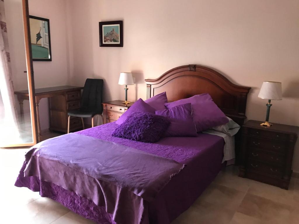 a bedroom with a purple bed and a desk at Lacasadeyolandayedu in Medina del Campo