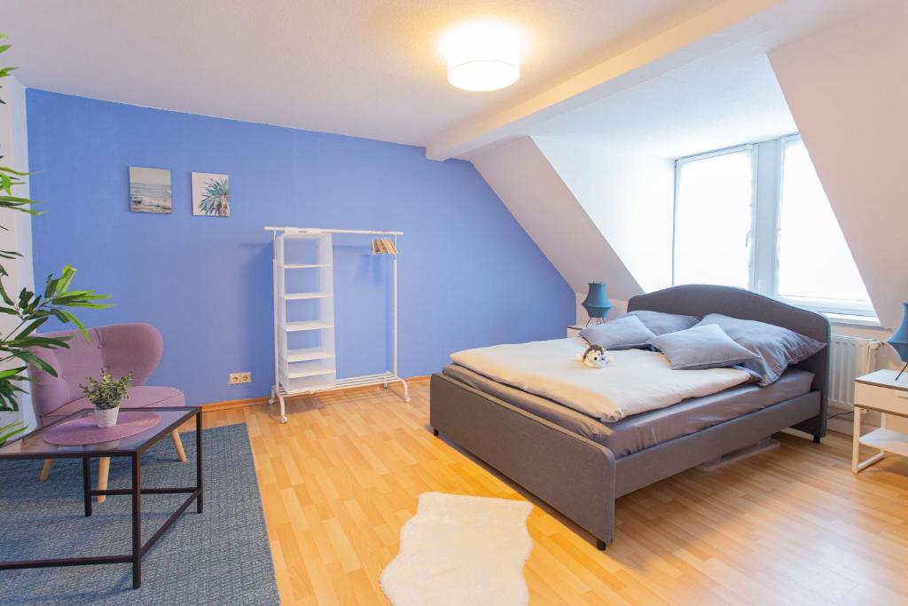1 dormitorio con cama y pared azul en FULL HOUSE Studios - Brühl's Skyline Apartment - Nespresso inkl, en Chemnitz