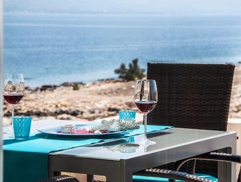 uma mesa com dois copos de vinho na praia em Atrium Blue Holiday House em Ražanac