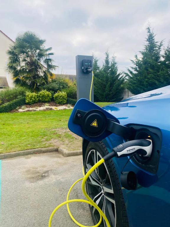 a blue car with a yellow hose plugged into a car charger at Kyriad Hotel Meaux in Meaux