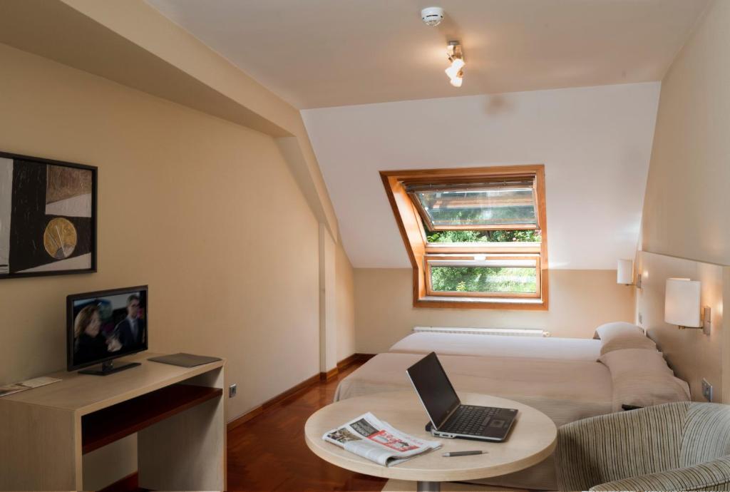 a bedroom with a bed, desk and a television at Apartamentos Attica21 Portazgo in A Coruña