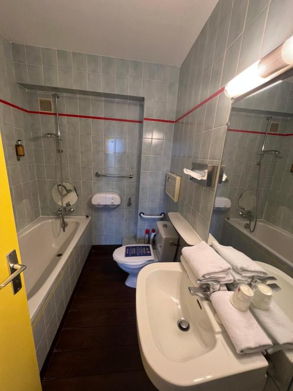 a bathroom with a sink, toilet and bathtub at Hotel Arcantis Le Voltaire in Rennes