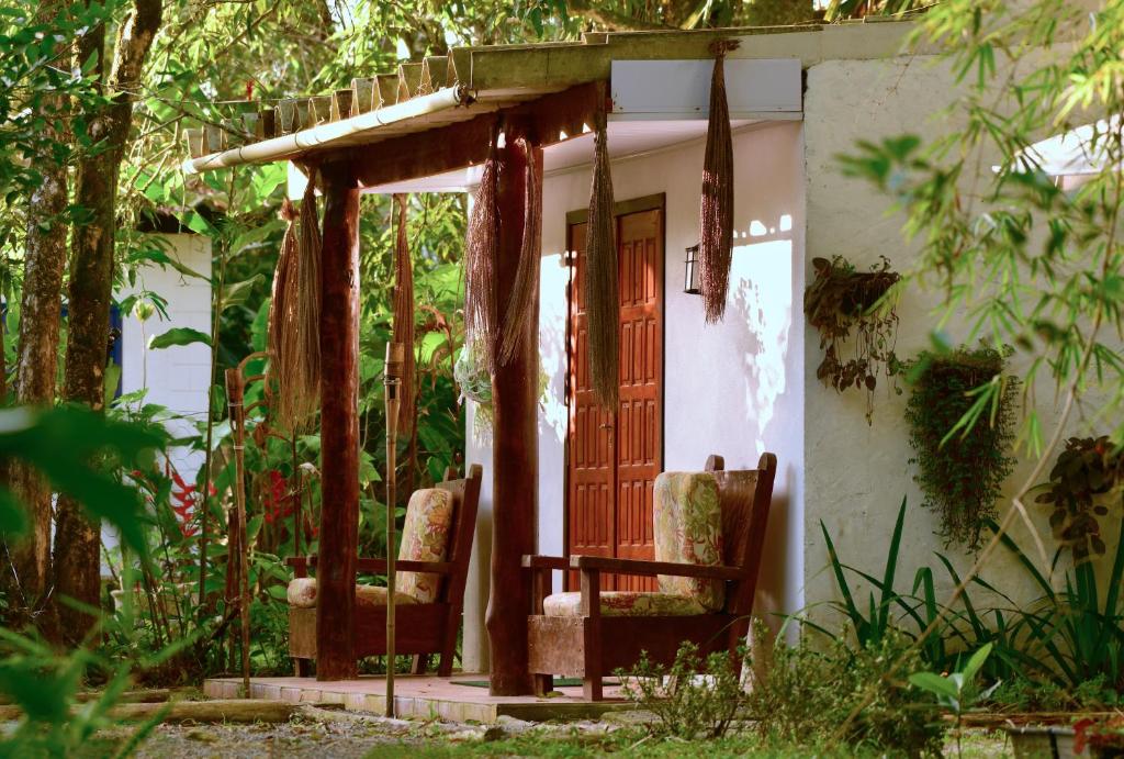 a porch of a house with two chairs and a door at Casa à beira do rio Jaguareguava na Mata Atlântica em Bertioga SP in Bertioga