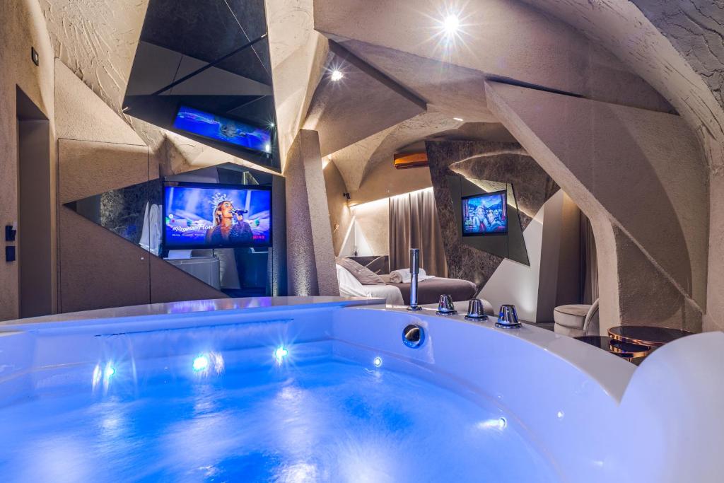 uma grande banheira num quarto com duas televisões em Le Suites Del Duomo Luxury em Catânia