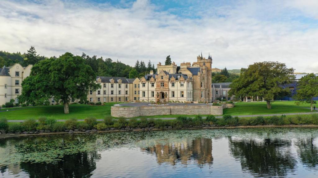 a large castle sitting next to a body of water at Cameron House on Loch Lomond in Balloch