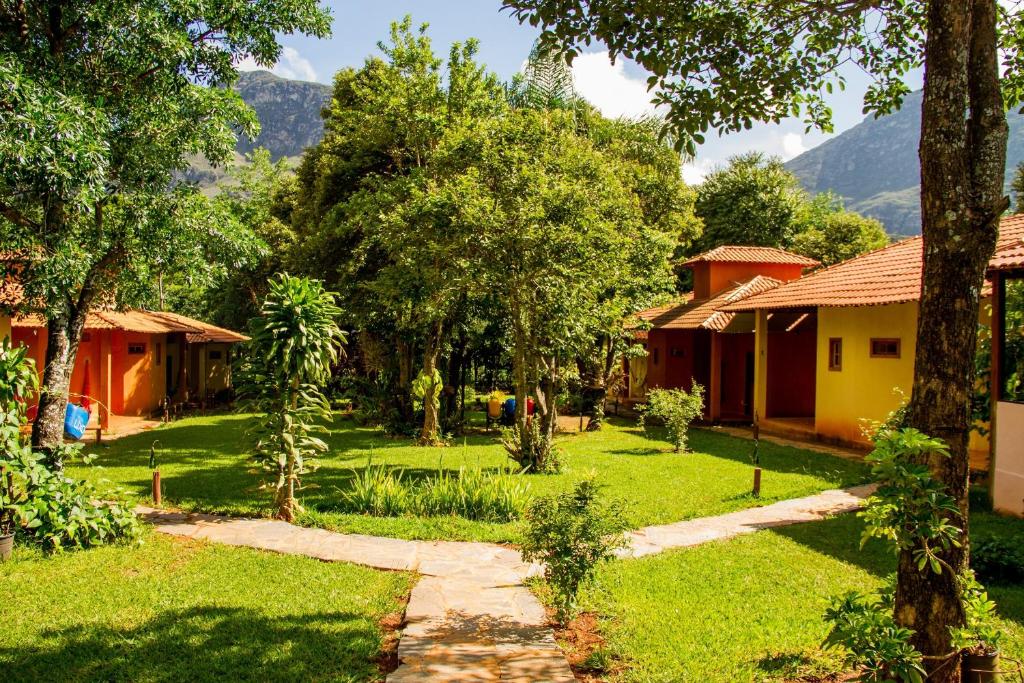 a garden with houses and trees and a path at Pousada Opicodocipo in Santana do Riacho