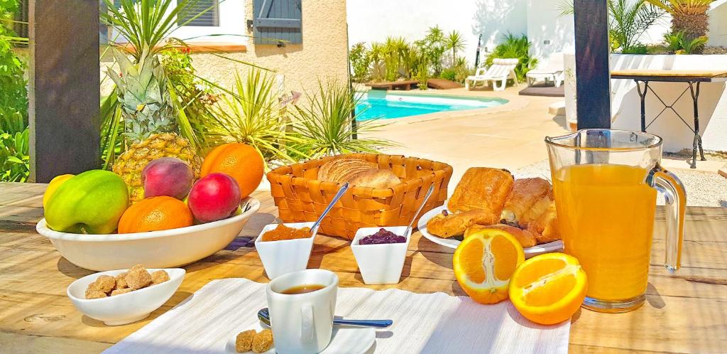 a table with breakfast foods and a glass of orange juice at VILLA REIALA Carry-le-Rouet in Carry-le-Rouet