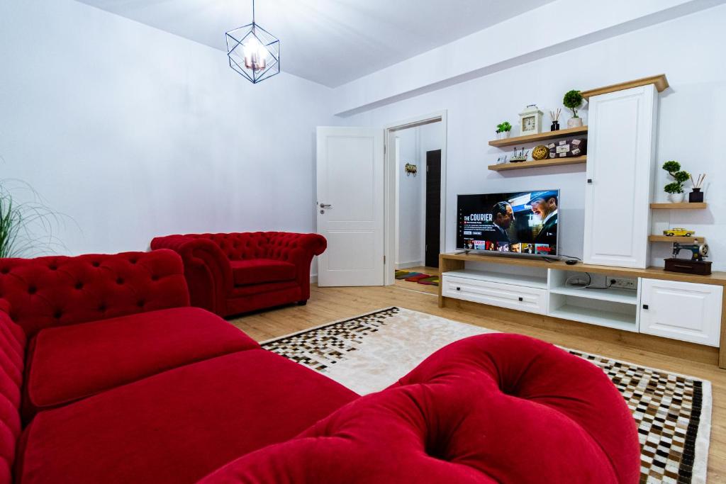 a living room with a red couch and a tv at Lighthouse Central Apt with unique views of the Fortress, Free Parking, 5 min by car from the Old Town in Braşov