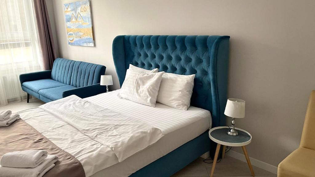 a bed with a blue headboard and a blue chair at Opera Center Hotel & Apartments in Lviv