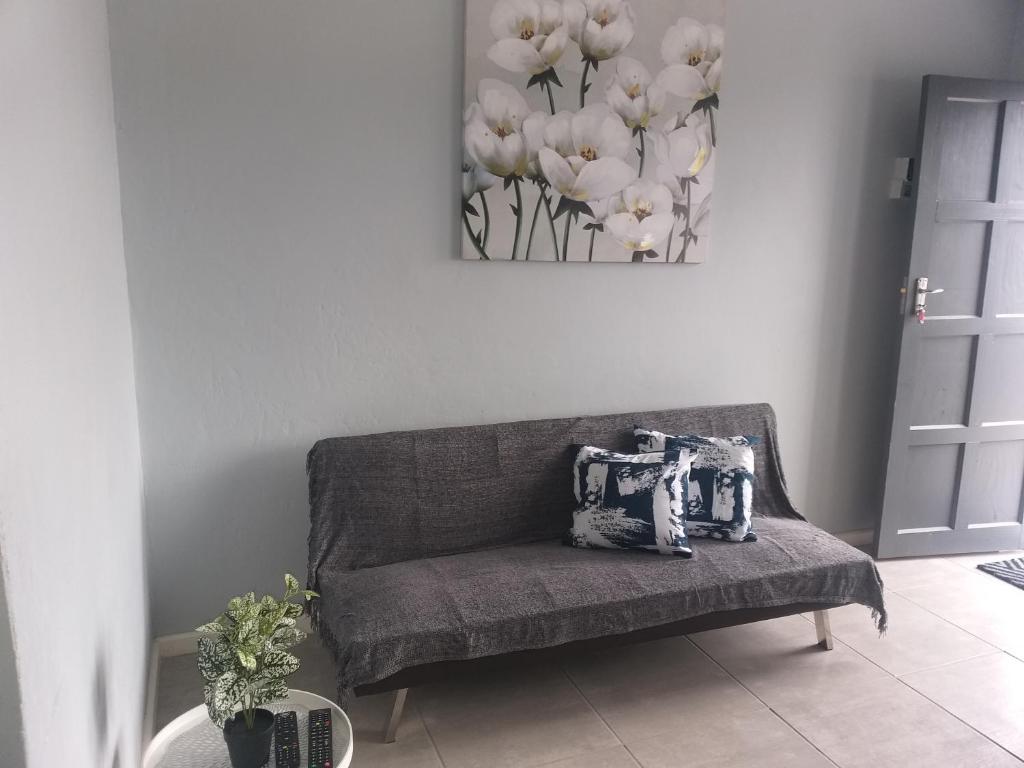 a couch in a living room with a picture of flowers at TJ Self-catering in Graaff-Reinet