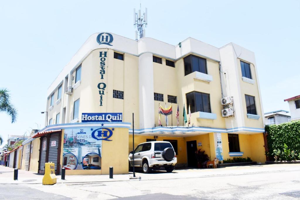 un edificio de hotel con un camión estacionado frente a él en Hostal Quil, en Guayaquil