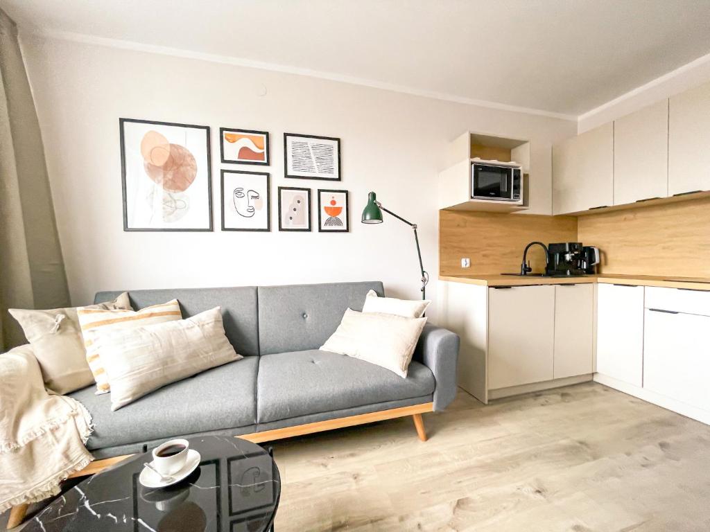 a living room with a couch and a kitchen at Apartament IV piętro in Ustka