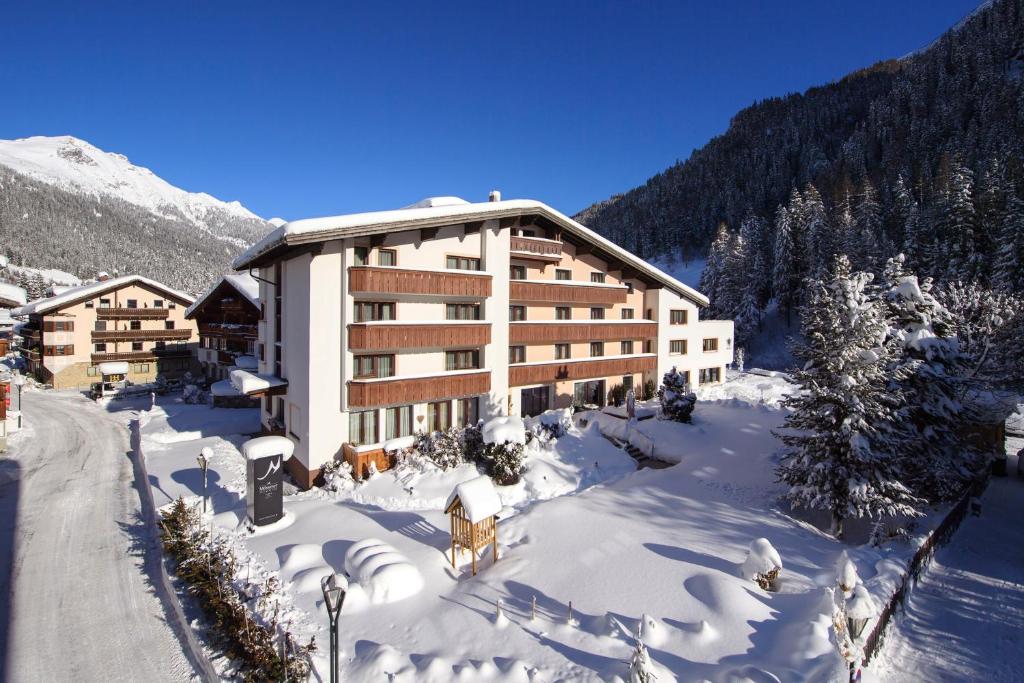 a large building in the snow with snow at "Quality Hosts Arlberg" Hotel Garni Mössmer in Sankt Anton am Arlberg