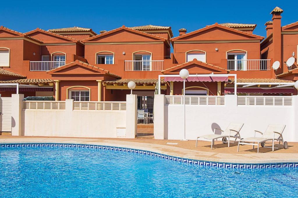 a villa with a swimming pool in front of a house at Bungalow Java - Plusholidays in Calpe