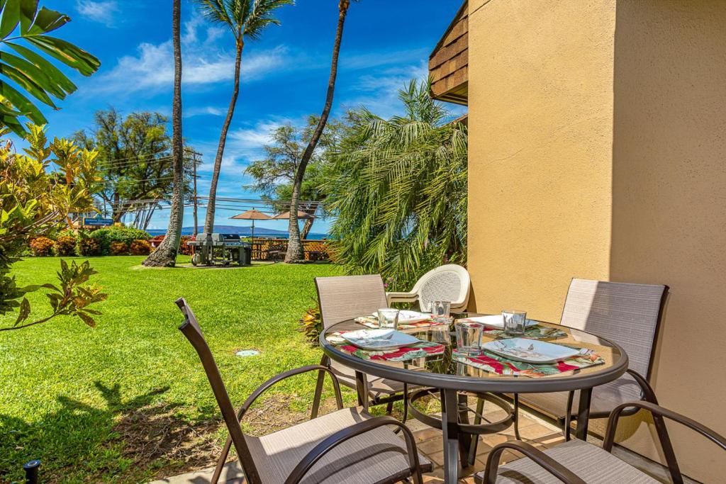a table and chairs on a patio with a view of the ocean at Kamaole Beach Club C109 in Kihei