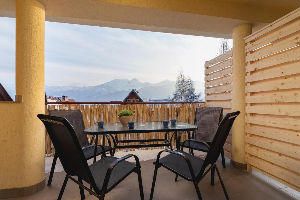 un patio con tavolo e sedie sul balcone. di Mountain View Pod Blachówką Apartments by Renters a Kościelisko