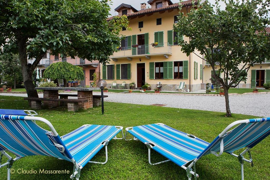 dwa niebieskie krzesła siedzące w trawie przed budynkiem w obiekcie Agriturismo Fruttirossi w mieście Trofarello