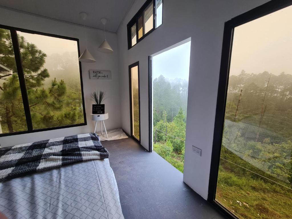 1 dormitorio con ventanas grandes y 1 cama con vistas en Vita Mountain Lodge en Santa Lucía