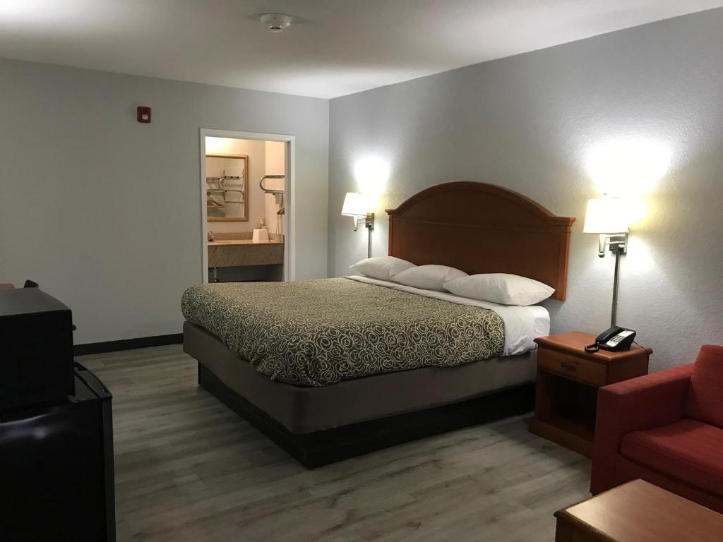 a hotel room with a bed and a red chair at Walnut Inn - Checotah in Checotah