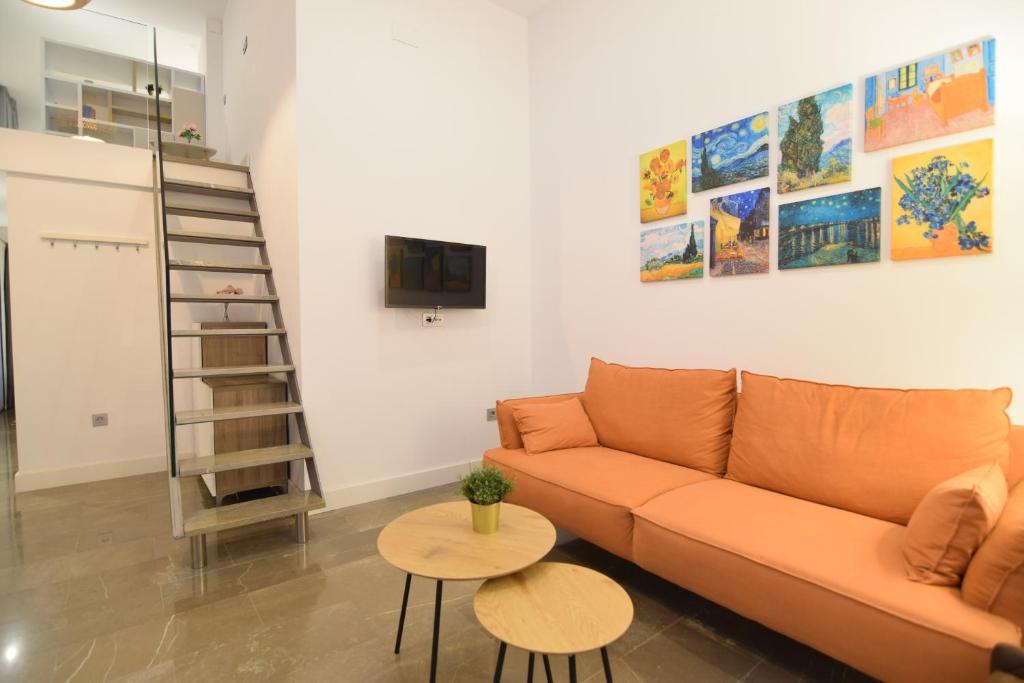 sala de estar con sofá y TV en la pared en Loft Van Gogh, Centro Histórico, en Málaga