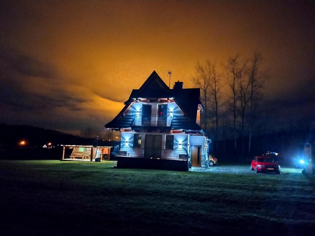 a house lit up at night in a field at Jurgowski Domek in Jurgów