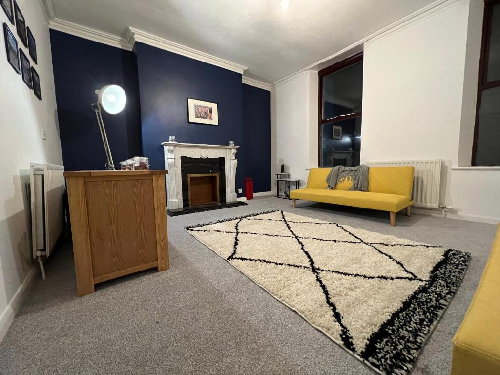 a living room with a yellow couch and a fireplace at Portland View Apartment in Carlisle