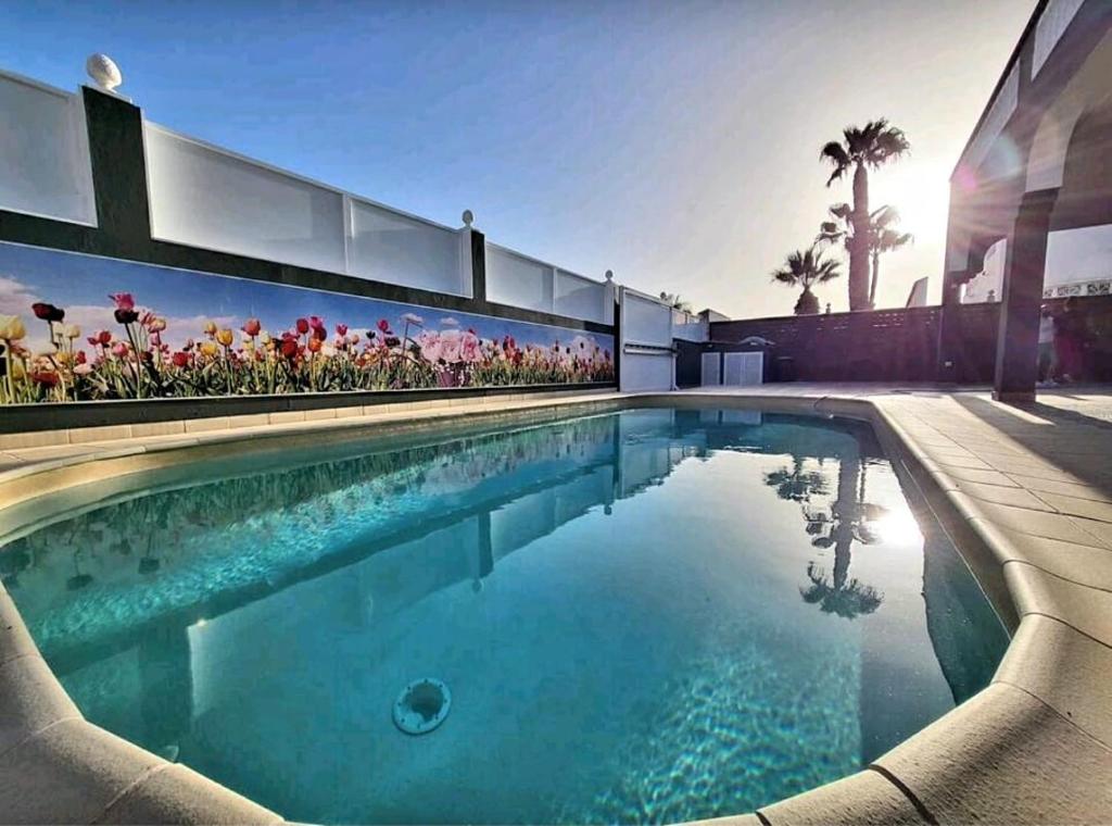 una piscina frente a una casa con flores en La VILLA DE ALISA La Casa Entera, en Maspalomas