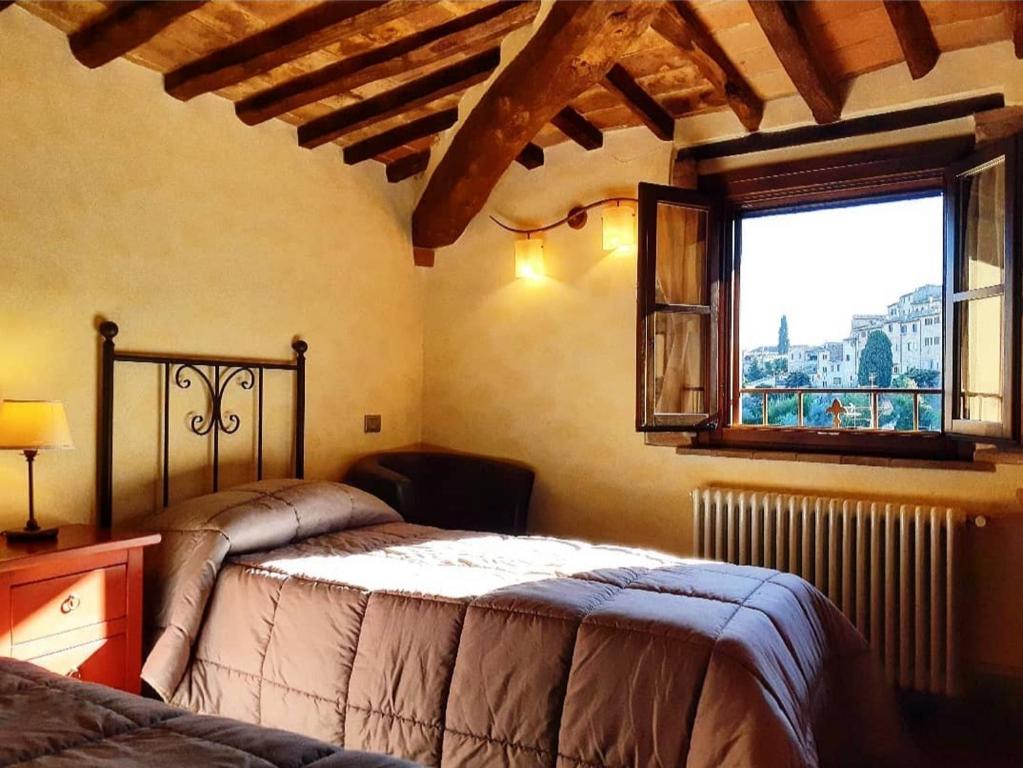 sypialnia z dużym łóżkiem i oknem w obiekcie Le Torri San Gimignano Apartments w mieście San Gimignano