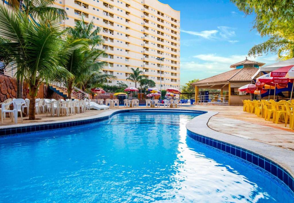 una piscina en el complejo con sillas y sombrillas en Golden Dolphin Roberto Imóveis, en Caldas Novas
