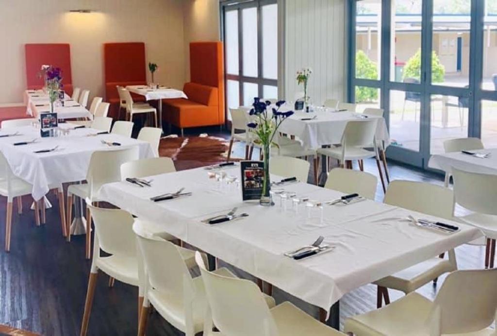 a room with white tables and white chairs and windows at Banana Hotel Motel in Banana