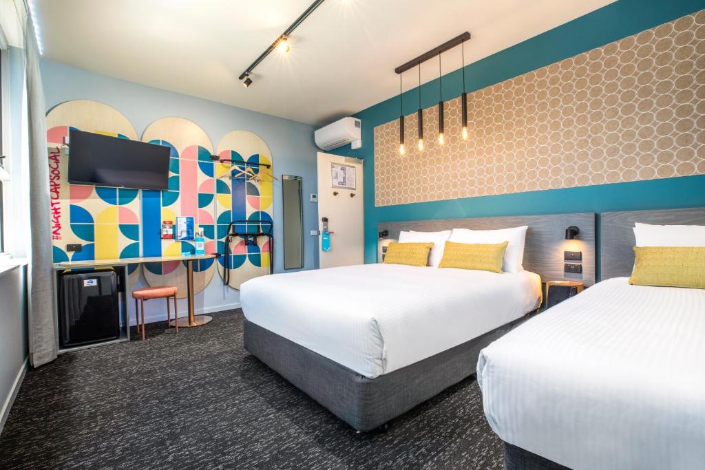 メルボルンにあるRoyal Hotel by Nightcap Socialのベッド2台とテレビが備わるホテルルームです。