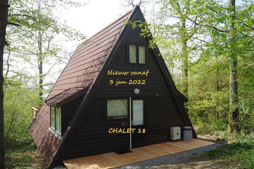 a black house with a brown roof in the woods at ArdennenVakantieBungalow in Durbuy