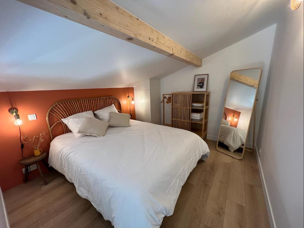 a bedroom with a large white bed and a mirror at Les Embruns, océan et centre ville à pied in Capbreton