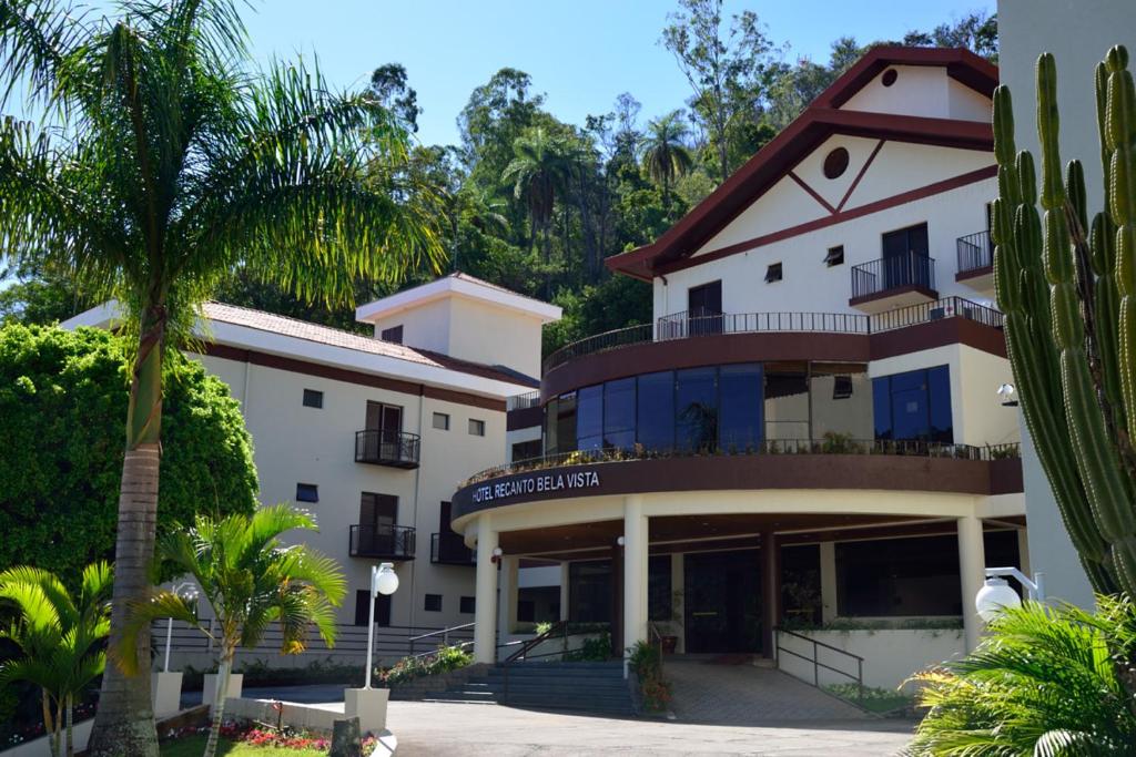 a building with a palm tree in front of it at Hotel Recanto Bela Vista in Águas de Lindóia