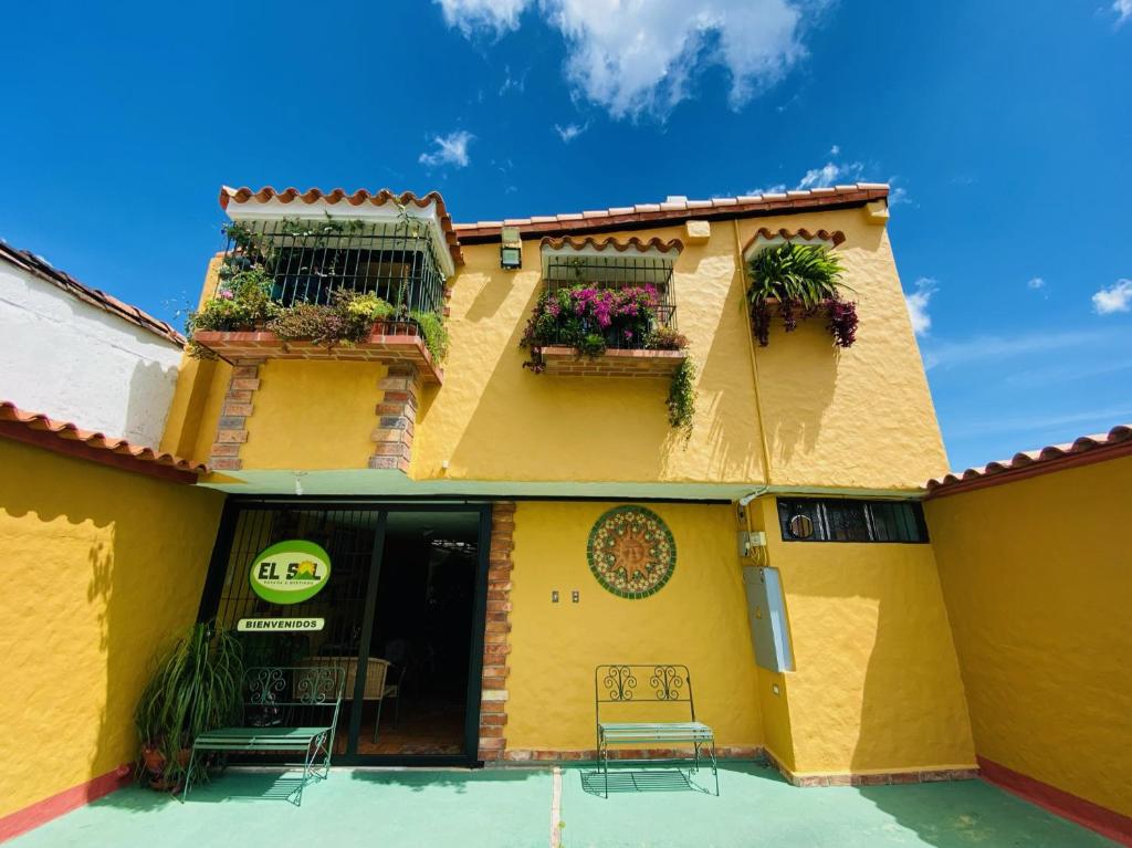 un edificio amarillo con 2 balcones con plantas. en El Sol Posada, en San Cristóbal