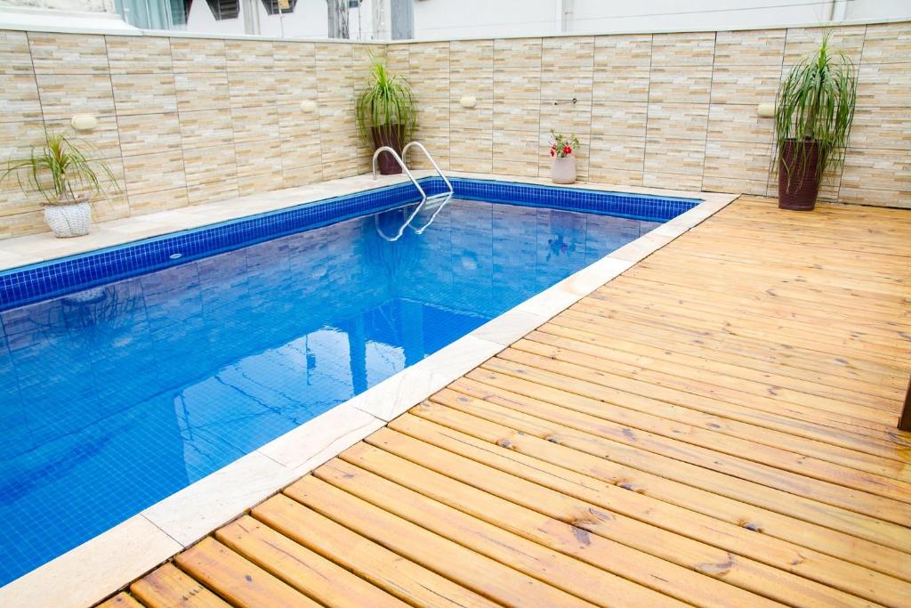 a large swimming pool with a wooden floor at NOVO Casa com piscina no centro de Caraguatatuba in Caraguatatuba