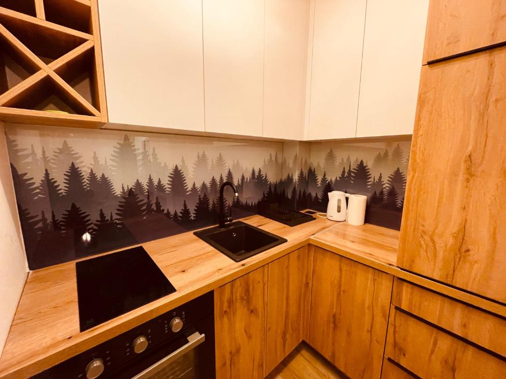 eine Küche mit einem Waschbecken und ein Wandbild aus dem Wald in der Unterkunft Apartman Pinewood Divcibare in Divčibare