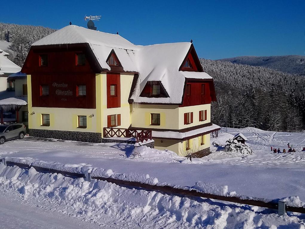 ein großes Haus mit Schnee auf dem Dach in der Unterkunft Penzion Martin in Janské Lázně