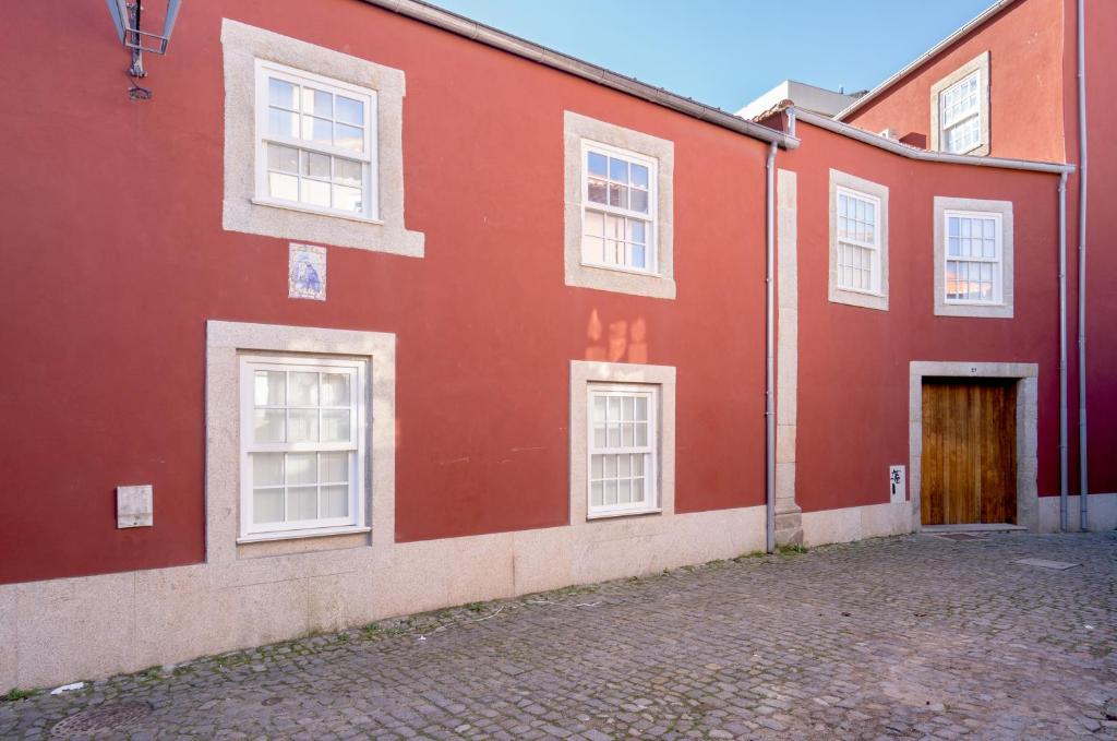 a red building with white windows and a door at Habitatio - Foz by LuxiStay in Porto