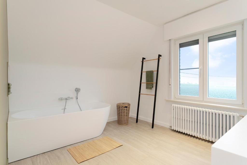 a white bathroom with a tub and a window at Vakantiewoning in het landelijke Staden! 10 pers - STAEDENBERGH in Staden