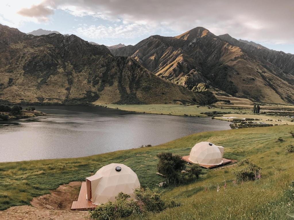 two tents on a hill next to a body of water at Glam camping Queenstown in Queenstown