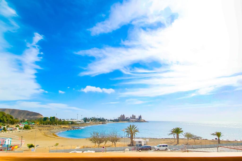 widok na plażę z palmami i oceanem w obiekcie Neues Apartment am Strand w mieście Arguineguín