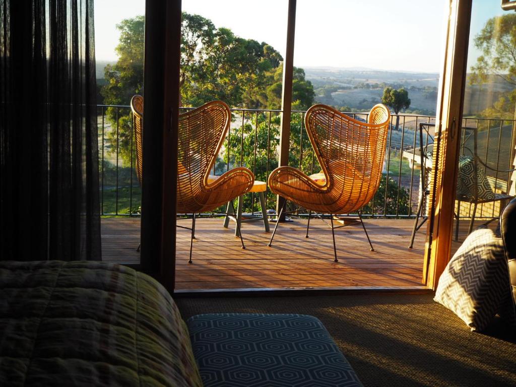 two wicker chairs sitting on a porch with a view at Shaws Road Winery B&B in Arthurs Creek