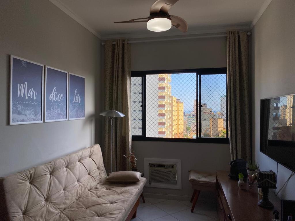 uma sala de estar com um sofá e uma grande janela em Apartamento 3 Dormitórios / Praia Enseada Guarujá, Piscina, Vista ao fundo e sol da manhã!. no Guarujá